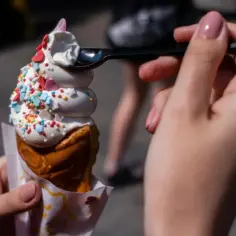 Lody w wafelku z kolorową posypką, jedzone łyżeczką.